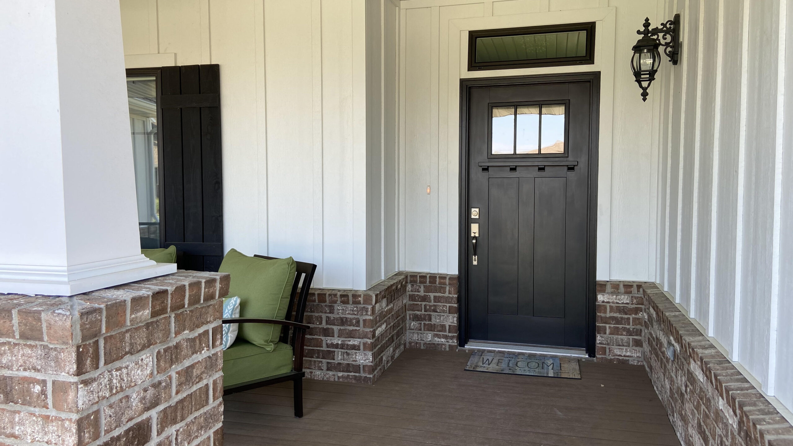 Front porch with a black front door and green chair